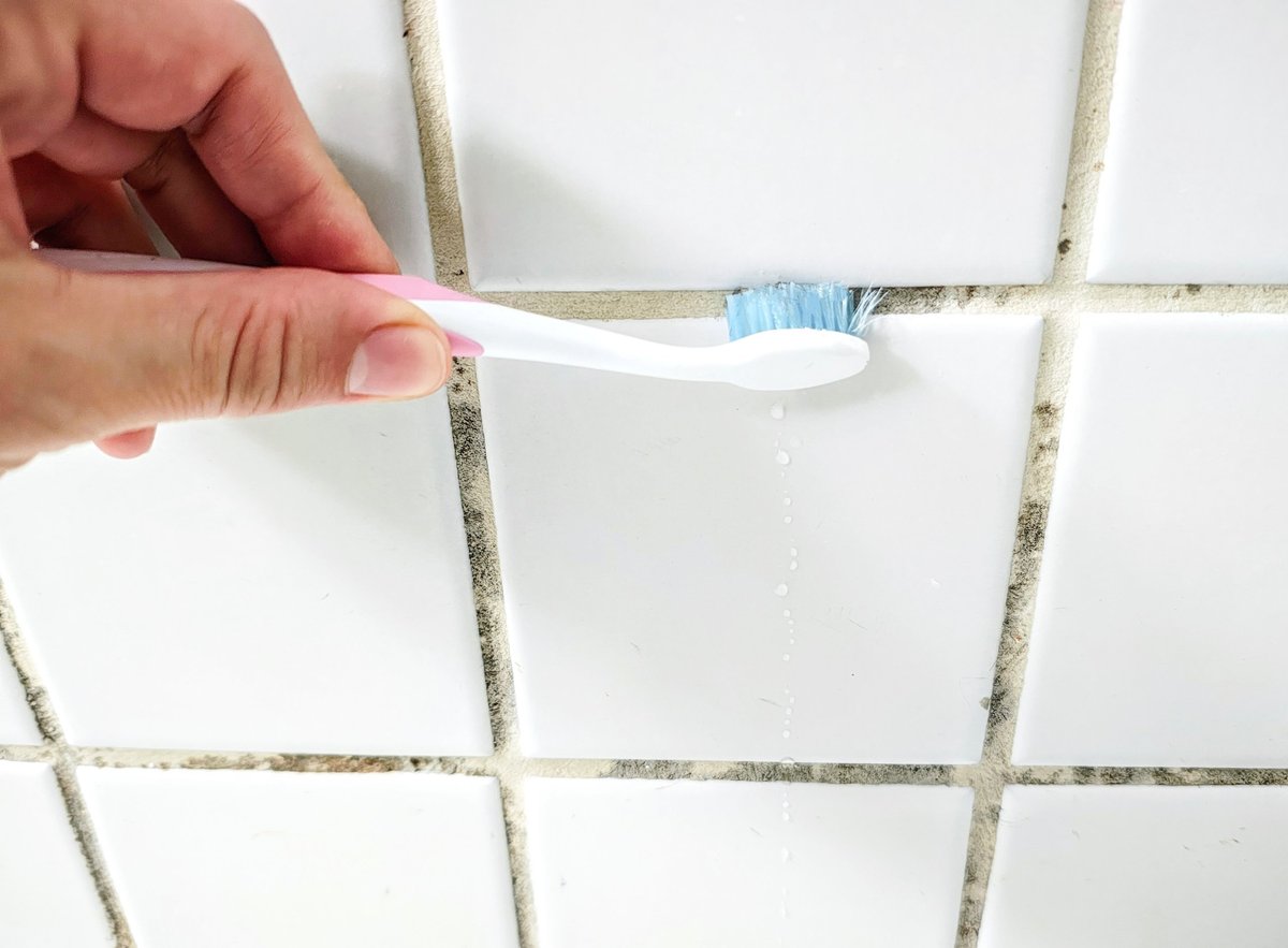 Person cleaning marble and grout to restore their shine