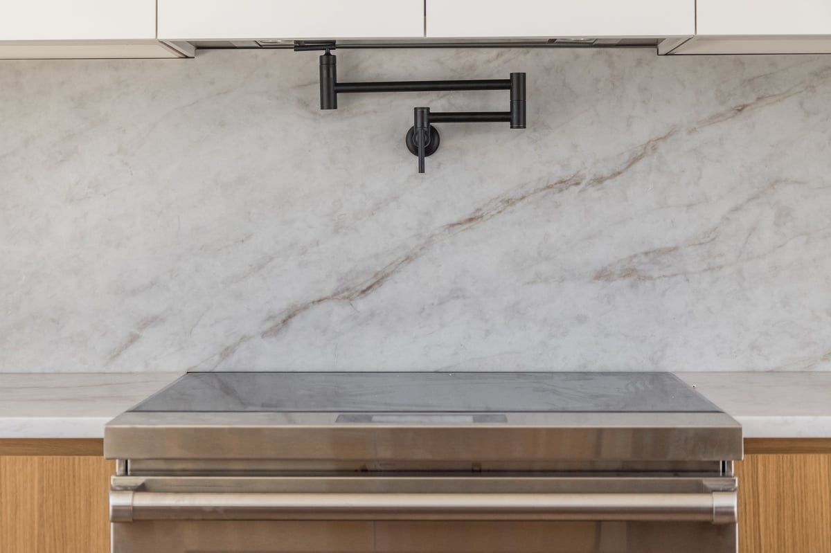 Stainless pot filler faucet above a stove, kitchen detail