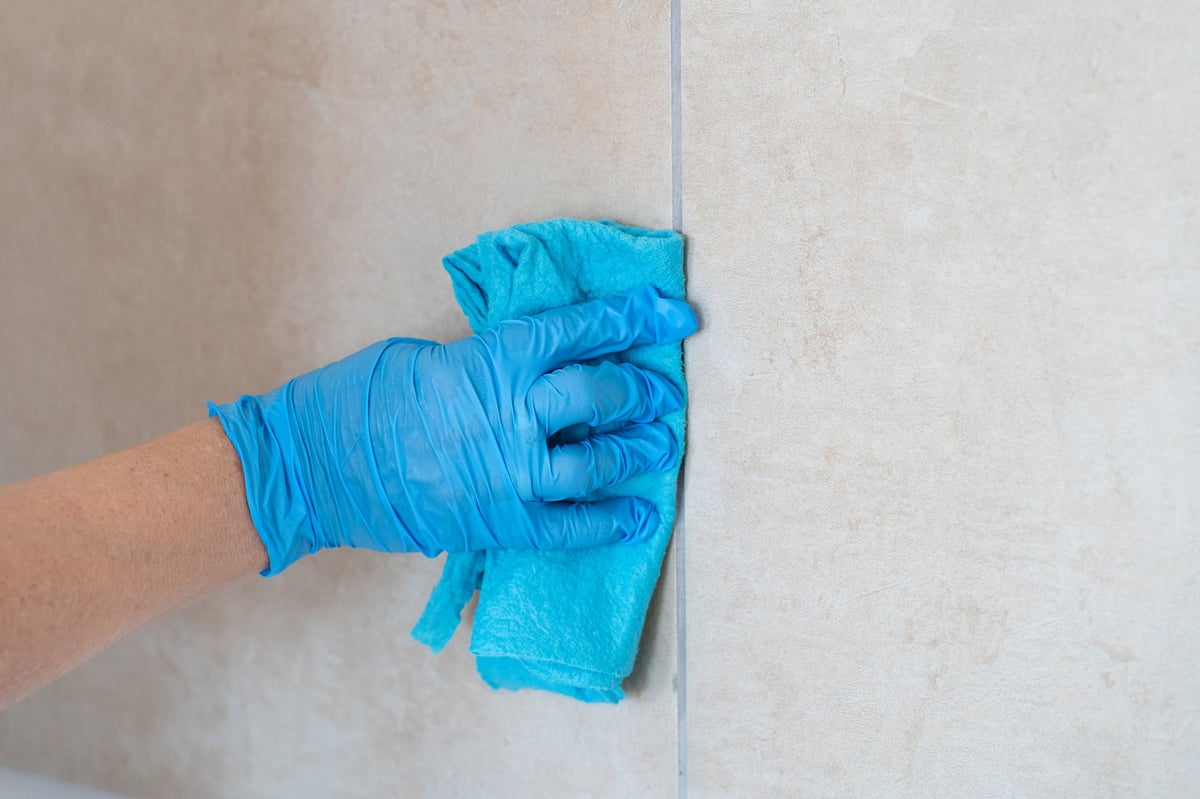 Person wiping ceramic wall tiles with a microfiber cloth