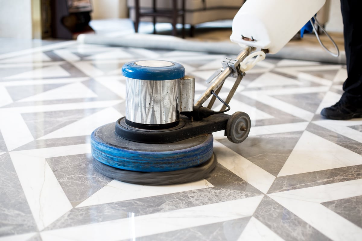 Marble technician diamond-honing and polishing a gleaming marble floor in a modern office building, restoring its depth and gloss dust-free